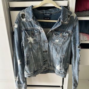 Denim jacket with white stars, rips showing camouflage pattern.